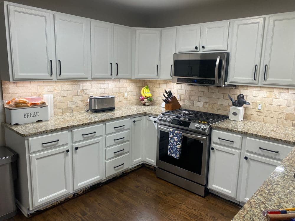 Modern kitchen featuring stainless steel appliances, gray cabinets, and wood-style flooring.
