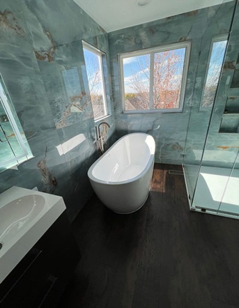 Modern bathroom featuring a freestanding tub, glass shower, and stunning marble walls.