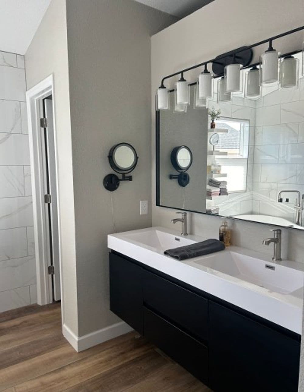 Modern bathroom with dual sinks, sleek black cabinetry, and stylish wall mirrors.