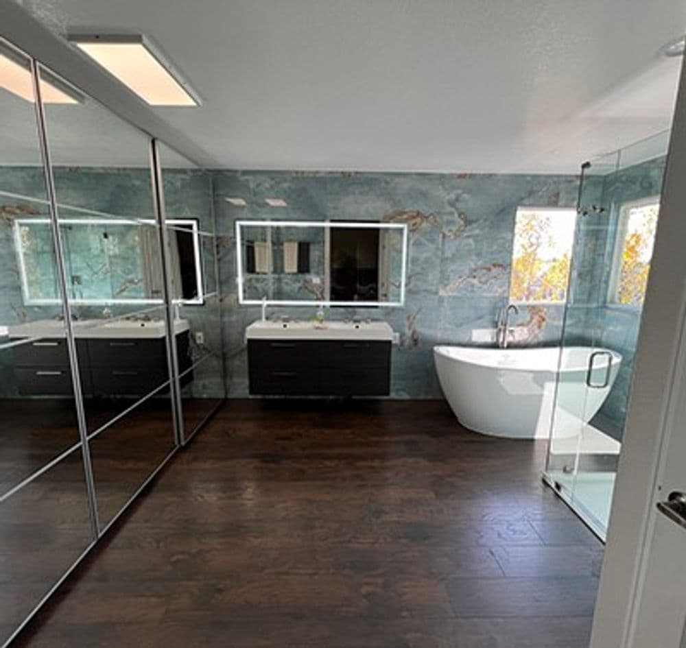 Modern bathroom featuring a freestanding tub, sleek vanity, and large mirrors with natural light.