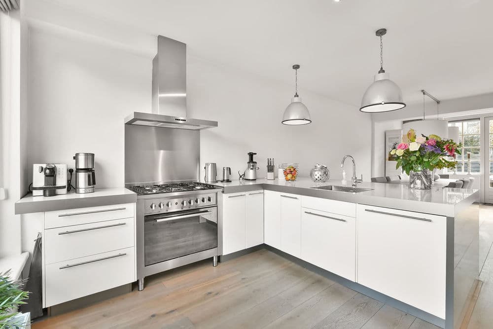 Modern white kitchen with stainless steel appliances, sleek cabinetry, and fresh flowers.