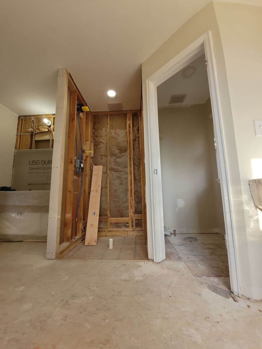 Renovation in progress: exposed wall framing and entrance to a bathroom in a home.