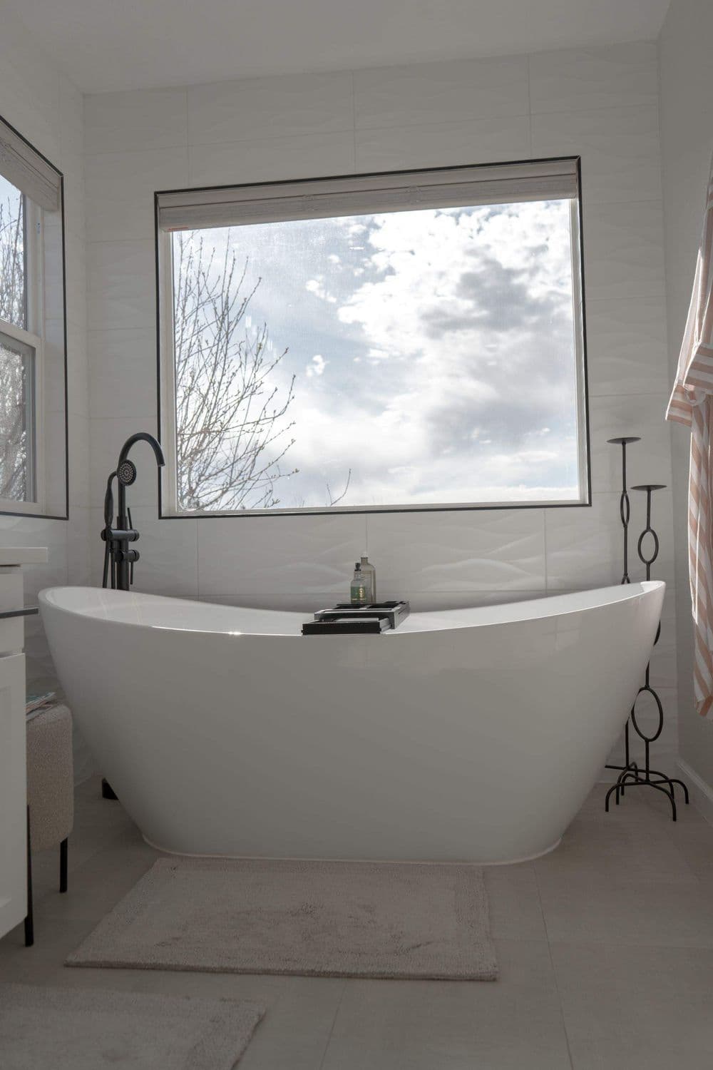 Modern bathroom with a freestanding bathtub, large window, and stylish decor.
