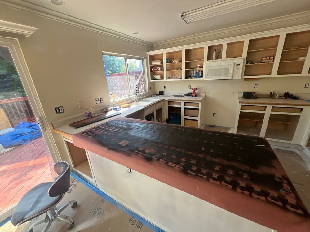 Renovated kitchen with a large countertop, unfinished cabinets, and sliding door access outdoors.